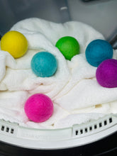 Load image into Gallery viewer, white blanket inside an open dryer with 6 multi-colored dryer balls on top of the blanket