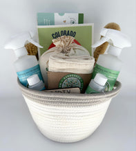 Load image into Gallery viewer, white woven basket filled with PUR Evergreen cleaning supplies:  two spray bottles, 2 'bottles of concentrated cleaner, produce bags, dryer balls, swedish dishcloth, bamboo brushes, and laundry detergent sheets