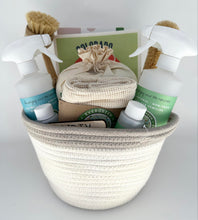 Load image into Gallery viewer, white woven basket filled with PUR Evergreen cleaning supplies:  two spray bottles, 2 'bottles of concentrated cleaner, produce bags, dryer balls, swedish dishcloth, bamboo brushes, and laundry detergent sheets