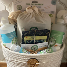 Load image into Gallery viewer, pur evergreen natural home bundle - basket that contains 2-16oz spray bottles + 2-2 oz refill bottles + beeswax wraps + swedish dishcloth + wool dryer balls + mesh produce bags