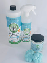 Load image into Gallery viewer, large bottle of cleaner with blue label, spray bottle next to it, in front is a jar with black lid, in the very front 4 flower shaped shower steamers
