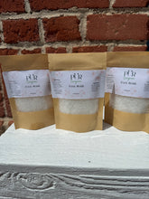 Load image into Gallery viewer, 3.5 oz Foot soak in paper packaging. Packages are on top of white box with brick background. Picture of 3 packages.  Ingredients include sea salt mix, peppermint oil, epsom salt, vitamin e oil, and apricot oil. This blend is soothing and a perfect way to relax your feet after a long day. 