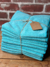 Load image into Gallery viewer, Stack of turquoise towels tied with twine against a brick wall.
