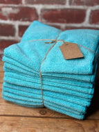 Stack of turquoise towels tied with twine against a brick wall.