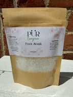 3.5 oz Foot soak in paper packaging. Package is on top of a white box with brick background. Ingredients include sea salt mix, peppermint oil, epsom salt, vitamin e oil, and apricot oil. This blend is soothing and a perfect way to relax your feet after a long day. 