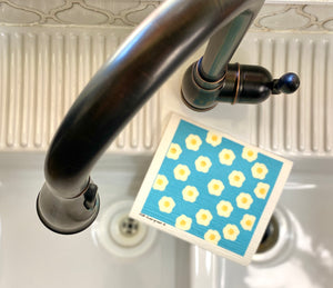 An eco-friendly Swedish dishcloth made from a blend of cotton and cellulose, with a textured surface for easy cleaning and scrubbing. The cloth is thin yet durable, and can be easily wrung out to remove excess water. It is shown in a variety of colors and patterns, with a label that reads 'Swedish Dishcloth